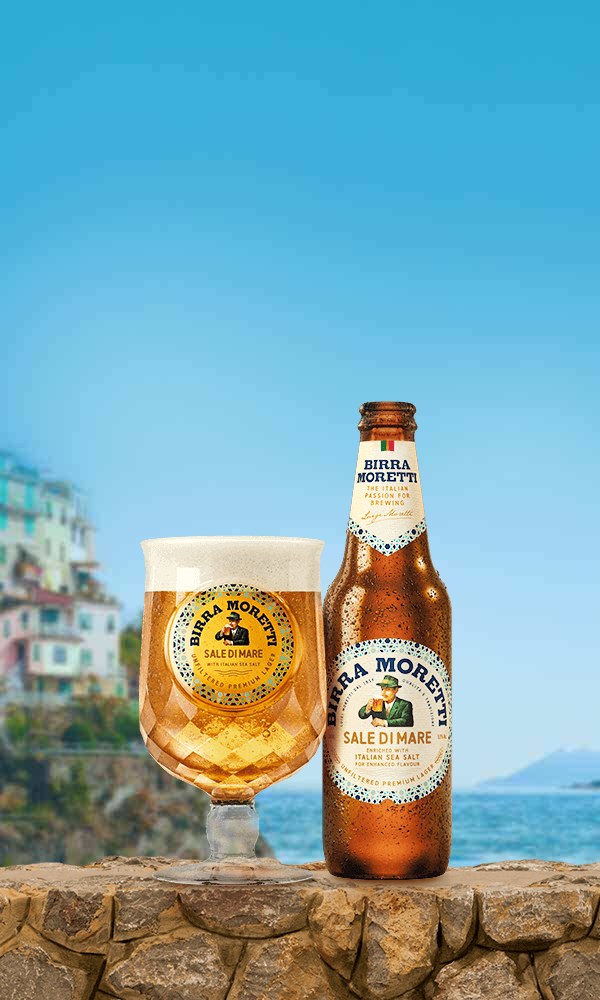 Glas en fles Birra Moretti Sale di Mare op een kademuur aan de Italiaanse kust
