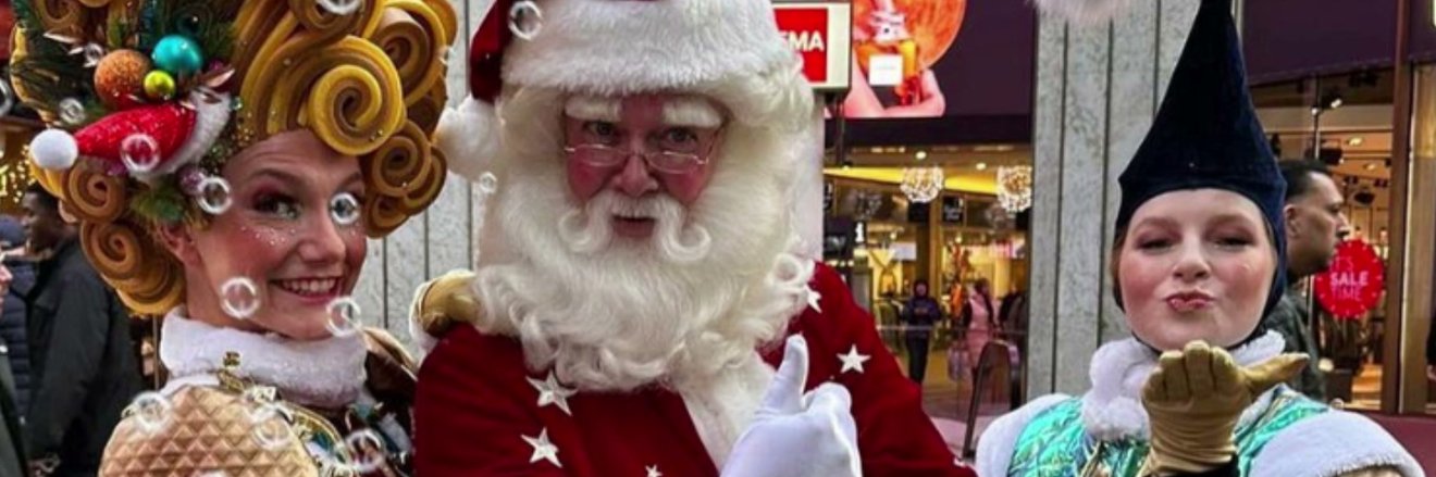 Kerstman met twee figuranten in de winkelstraat