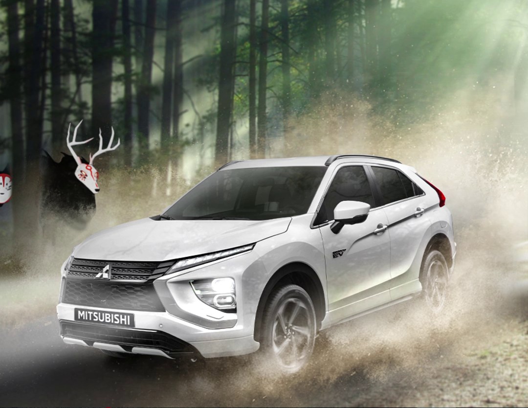 Eclipse Cross PHEV door het stof in een bos, een hert kijkt toe