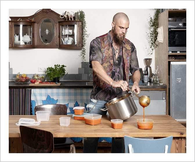 De foto vult de banner: een man schenkt soep in bakjes