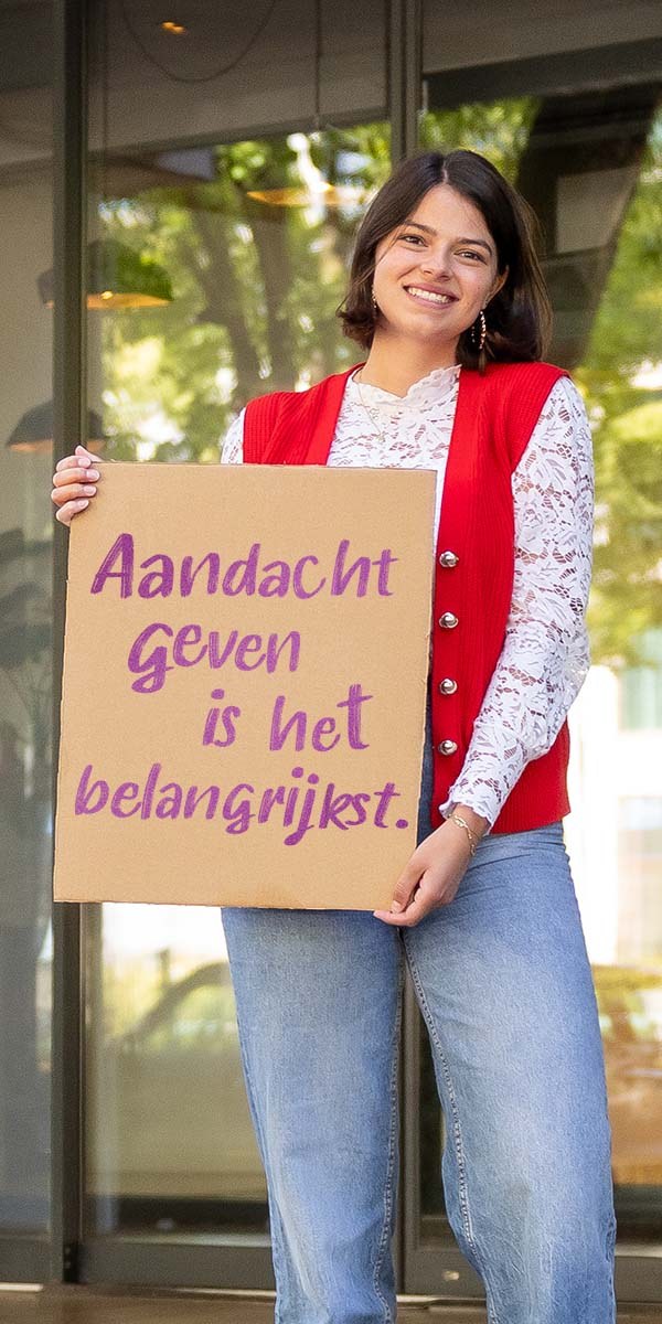 Vrijwilliger met het bord Aandacht geven is het belangrijkst
