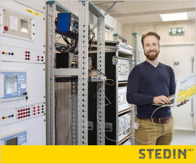 Engineer met laptop tussen de schakelkasten
