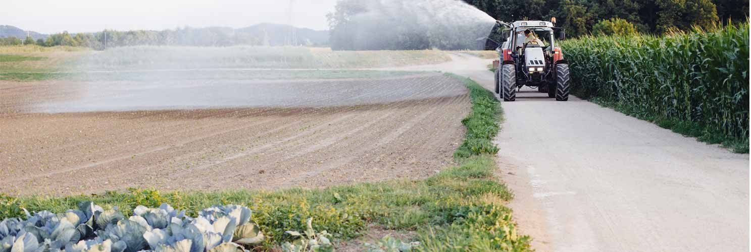 Een tractor besproeit een droge akker