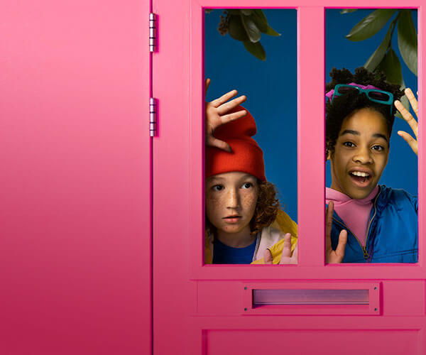 Twee kinderen kijken door de ramen van een roze deur