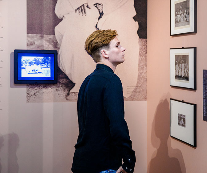 Een bezoeker kijkt naar foto's aan een roze wand