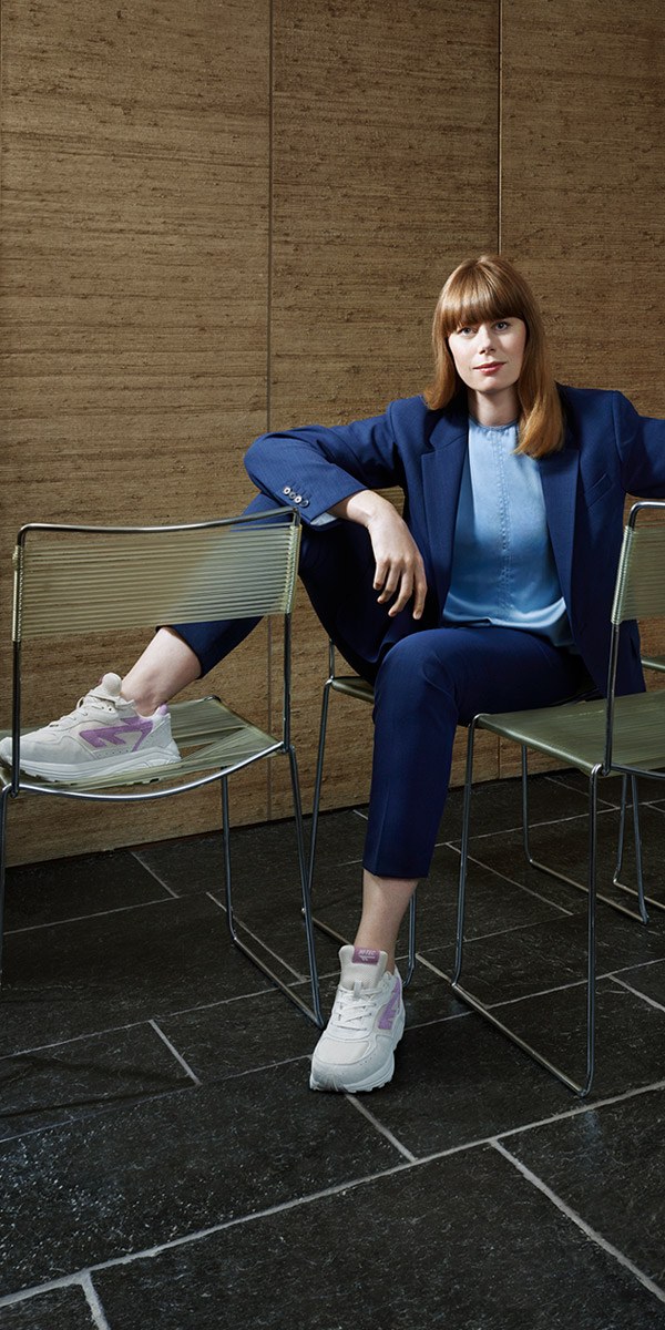 Margot in een blauw pak op een stoel